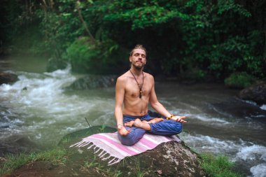 Yoga uygulaması ve doğada meditasyon. Nehir yakınlarında pratik yapan adam
