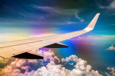 Gökkuşağı etkisi ile bulutlu gökyüzünde uçağın Kanadı