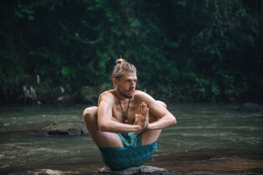 Yoga uygulaması ve doğada meditasyon. Nehir yakınlarında pratik yapan adam