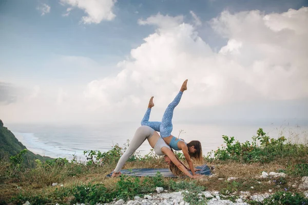 Coppia di ragazze pratica yoga sullo sfondo dell'oceano — Foto Stock