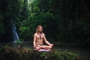 Yoga uygulaması ve doğada meditasyon. Nehir yakınlarında pratik yapan adam