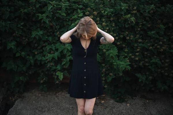 Romantická dívka v černých šatech na zeleném vegetativním pozadí — Stock fotografie