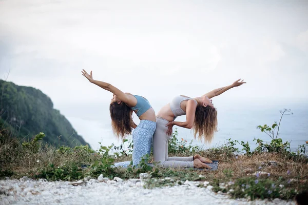 Coppia di ragazze pratica yoga sullo sfondo dell'oceano — Foto Stock