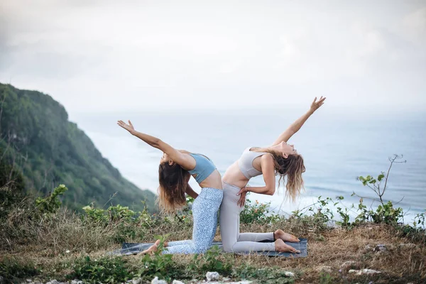 Coppia di ragazze pratica yoga sullo sfondo dell'oceano — Foto Stock