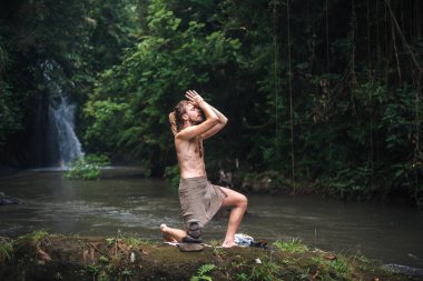 Yoga uygulaması ve doğada meditasyon. Nehir yakınlarında pratik yapan adam