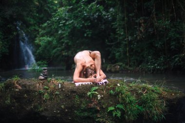 Yoga uygulaması ve doğada meditasyon. Nehir yakınlarında pratik yapan adam