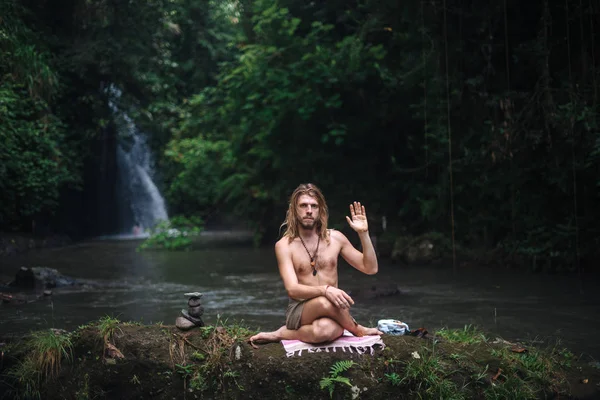 Yoga uygulaması ve doğada meditasyon. Nehir yakınlarında pratik yapan adam