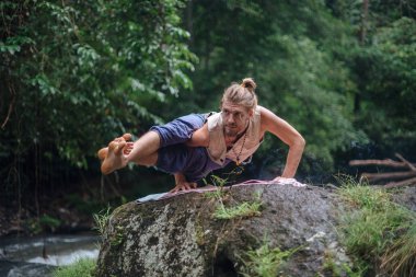 Yoga uygulaması ve doğada meditasyon. Nehir yakınlarında pratik yapan adam