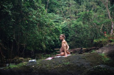 Yoga uygulaması ve doğada meditasyon. Nehir yakınlarında pratik yapan adam
