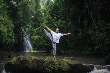 Yoga uygulaması ve doğada meditasyon. Nehir yakınlarında pratik yapan adam