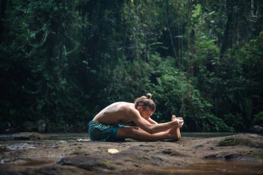 Yoga uygulaması ve doğada meditasyon. Nehir yakınlarında pratik yapan adam