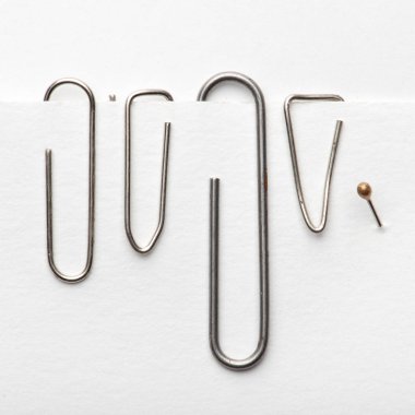 Ataşlar kağıt tutar. Beyaz arka planda iğneler