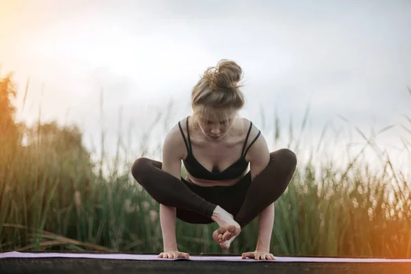 Chica practica yoga temprano por la mañana en el muelle — Foto de Stock