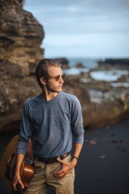 Sahilde gitar çalan romantik bir genç adam.