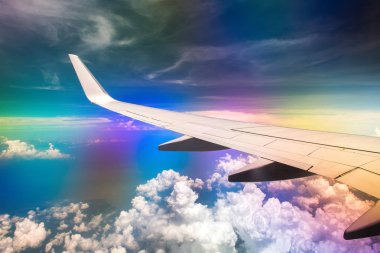 Gökkuşağı etkisi ile bulutlu gökyüzünde uçağın Kanadı