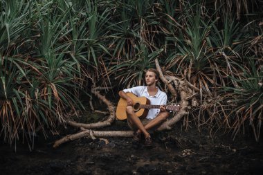 Sahilde gitar çalan romantik bir genç adam.