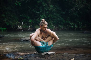 Yoga uygulaması ve doğada meditasyon. Nehir yakınlarında pratik yapan adam