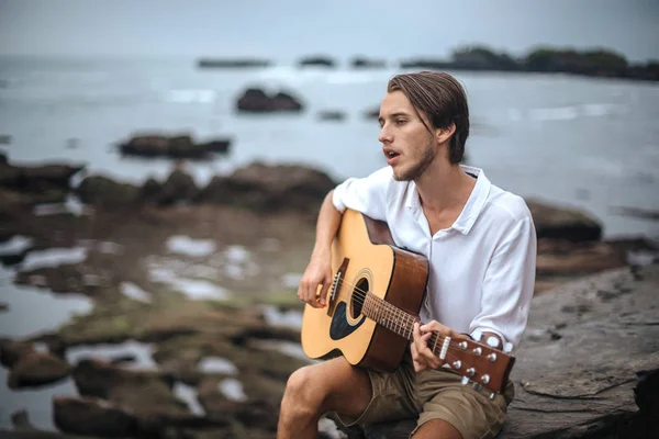 Romantische jongeman met een gitaar op het strand — Stockfoto