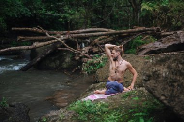 Yoga uygulaması ve doğada meditasyon. Nehir yakınlarında pratik yapan adam