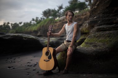 Sahilde gitar çalan romantik bir genç adam.
