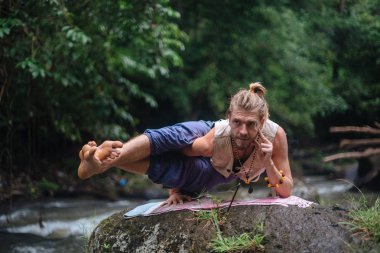 Yoga uygulaması ve doğada meditasyon. Nehir yakınlarında pratik yapan adam