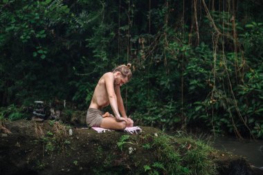 Yoga uygulaması ve doğada meditasyon. Nehir yakınlarında pratik yapan adam