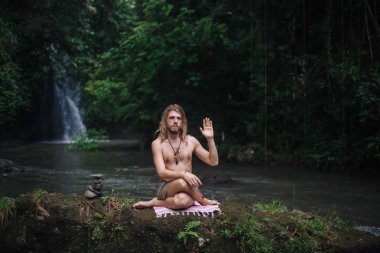 Yoga uygulaması ve doğada meditasyon. Nehir yakınlarında pratik yapan adam