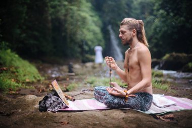 Yoga uygulaması ve doğada meditasyon. Nehir yakınlarında pratik yapan adam