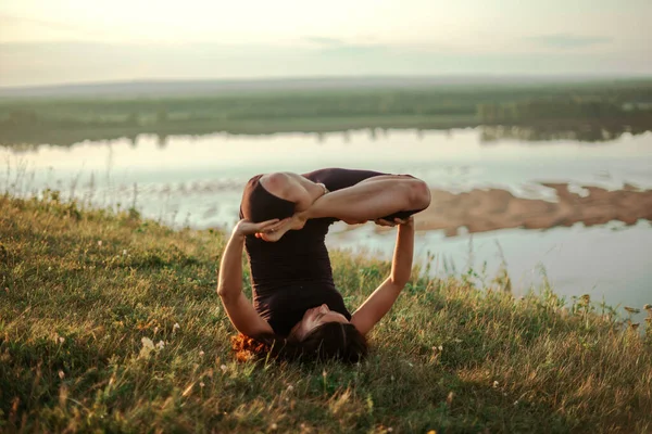 Cvičení jógy a meditace v přírodě při východu slunce. Žena cvičí u velké řeky Kama. — Stock fotografie