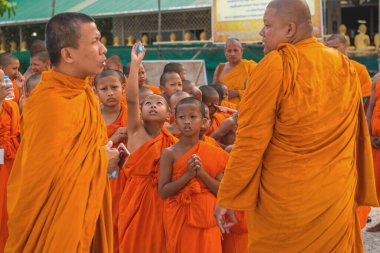 Tayland 'daki Phuket' teki Büyük Buda Tapınağı yakınlarında turuncu elbiseli genç Budistler. 28 Nisan 2019.