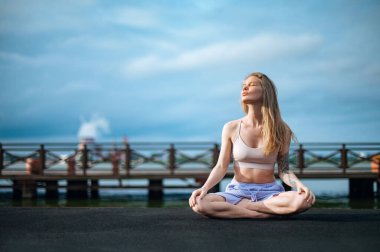 Yoga pratiği ve güneş doğarken meditasyon. Kadının biri rıhtımda pratik yapıyor..