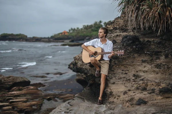 Romantische jongeman met een gitaar op het strand — Stockfoto