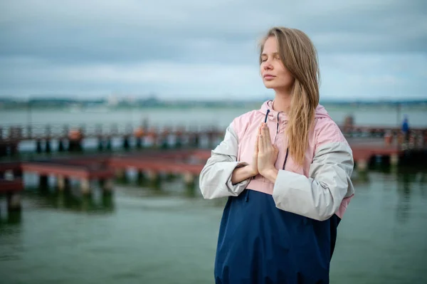 Yoga-Praxis und Meditation in der Natur bei Sonnenaufgang. Frau übt nahe City auf Seebrücke. — Stockfoto