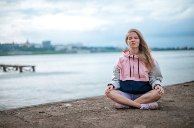 Yoga pratiği ve güneş doğarken meditasyon. Kadının biri rıhtımda pratik yapıyor..