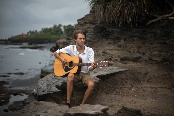 Romantic young man with a guitar on the beach — Stock Photo, Image