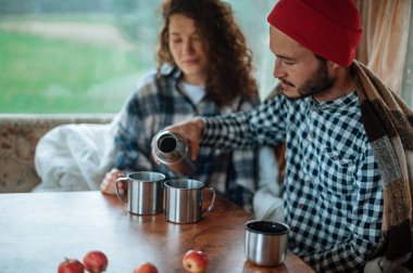 Karavanda bir masada oturan ve çay içen çift..