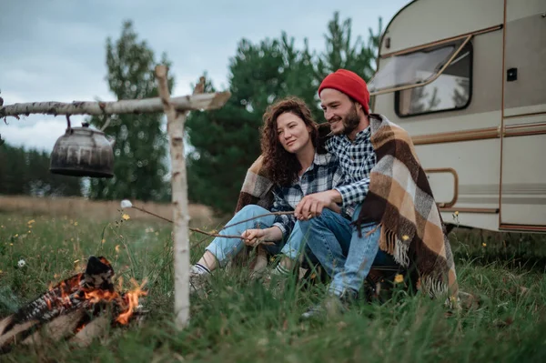 Couple dans un damier rôtissant des guimauves en feu près de la maison de la remorque — Photo