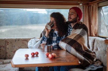 Karavanda bir masada oturan ve çay içen çift..