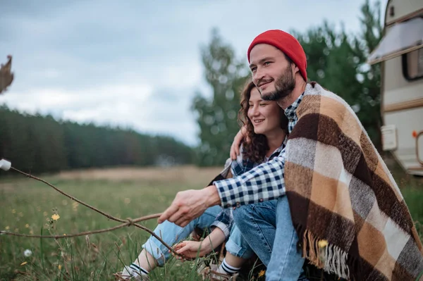 Pareja romántica pasando tiempo juntos cerca de casa remolque. Hombre barbudo guapo y mujer hermosa disfrutando de la compañía de los demás. Viajar juntos con autocaravana. Imagen de stock