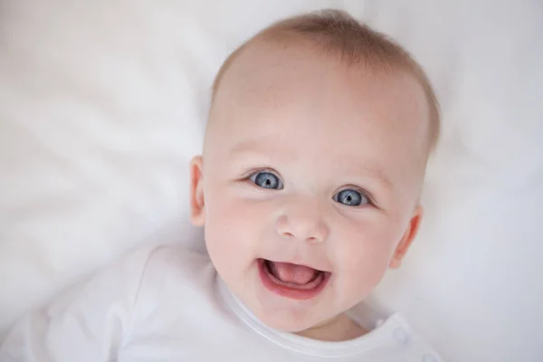 sırt üstü beyaz bir levha üzerinde mutlu gülümseyen çocuk yalan