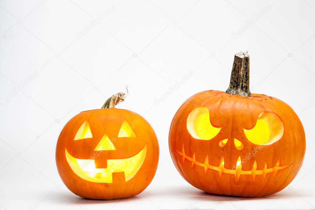 Two Halloween pumpkin head jack lantern with burning candles isolated on white background