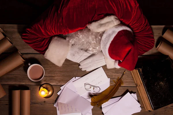 Weihnachtsmann sitzt am Tisch und schläft nach hartem Tag — Stockfoto