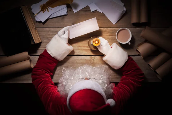 Weihnachtsmann sitzt am Tisch in seinem Zimmer und liest Weihnachtsbrief vom Kind — Stockfoto