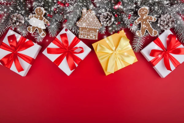 Cadeaux de Noël présents sur fond rouge. Sapin des neiges blanc snd boîtes-cadeaux dorées avec des noeuds de ruban et des décorations festives de vacances. Frontière inférieure horizontale. Vue supérieure avec espace de copie — Photo