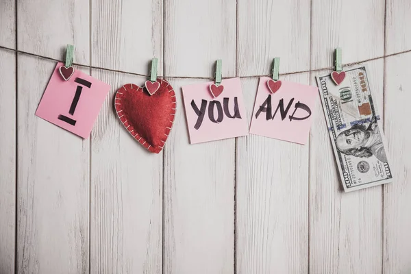 Cartão de Dia dos Namorados. Coração e folhas de papel na corda com palavras de amor no fundo de madeira branca velha — Fotografia de Stock