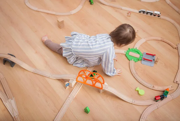 Ragazzo carino che gioca con la strada ferroviaria giocattolo a casa Immagine Stock