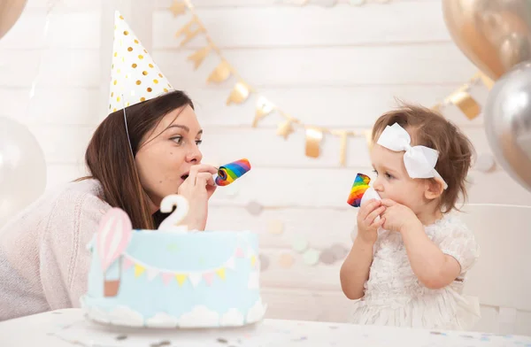 Baby birthday party. Mother and her daughter celebrate and fun together. Child party with balloons decoration and cake