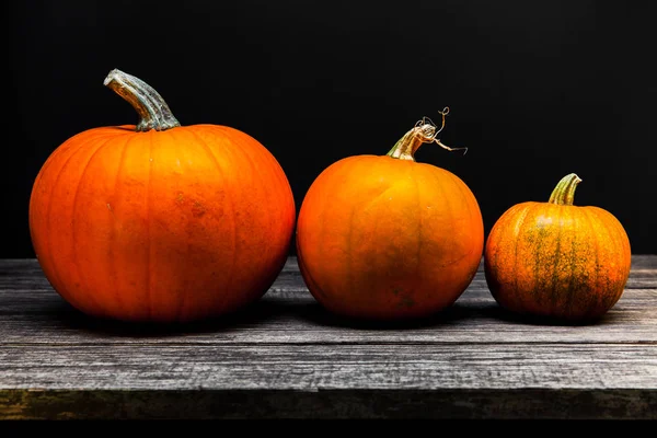 Drei Herbst-Halloween-Kürbisse auf hölzernem Hintergrund — Stockfoto