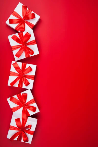 Boże Narodzenie biały prezent prezentuje na czerwonym tle. Widok z góry z przestrzenią kopiowania. Pionowe — Zdjęcie stockowe