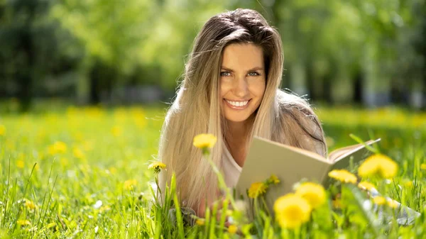 女性は緑の草の上にあり、本を読んで、屋外でリラックス — ストック写真